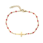 Cross bracelet in gold-plated metal with interlaced red pearls