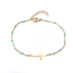 Cross bracelet in gold-plated metal with interlaced sky-blue pearls